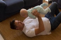 Father playing with his baby boy in living room at home — Stock Photo