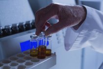 Close-up de cientista masculino colocando frascos médicos em uma máquina de laboratório em laboratório — Fotografia de Stock