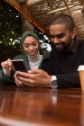 Happy couple using mobile phone in cafe — Stock Photo