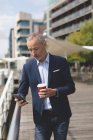 Бизнесмен пользуется мобильным телефоном на набережной в солнечный день — стоковое фото