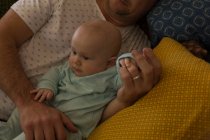 Padre y bebé niño relajándose en un sofá en casa - foto de stock