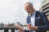 Geschäftsmann an einem sonnigen Tag mit digitalem Tablet an der Promenade — Stockfoto