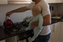 Padre y bebé niño preparando café en la cocina en casa - foto de stock