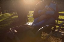 Батько годує молоко своєму дитині в парку в сонячний день — стокове фото