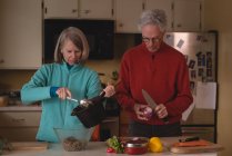 Старшая пара готовит еду на кухне дома — стоковое фото