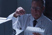 Homme scientifique plaçant une bouteille en verre à tube chimique sur une machine en laboratoire — Photo de stock