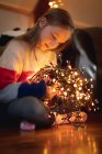 Nahaufnahme eines Mädchens, das zu Hause beleuchtete Lichter betrachtet — Stockfoto
