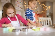 Siblings cutting cookies in the kitchen at home — Stock Photo