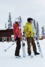Seitenansicht eines älteren Ehepaares, das mit Skistock und Skistock auf verschneiter Landschaft steht — Stockfoto