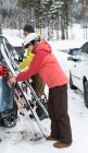 Pareja mayor manteniendo tabla de esquí y bastón de esquí cerca del coche durante el invierno - foto de stock
