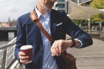 Geschäftsmann kontrolliert Zeit auf Smartwatch an der Promenade — Stockfoto