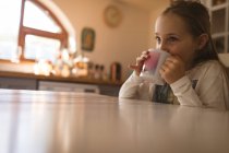 Улыбающаяся девушка пьет кофе дома — стоковое фото