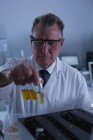 Homme scientifique plaçant une bouteille chimique sur une machine dans le laboratoire 4k — Photo de stock