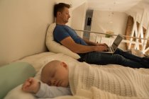 Junge schläft, während Vater Laptop im Schlafzimmer benutzt — Stockfoto