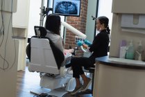 Une dentiste interagit avec un patient en clinique dentaire — Photo de stock