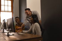 Счастливые коллеги по бизнесу обсуждают за компьютером в офисе — стоковое фото