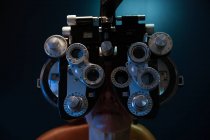 Primer plano del optometrista examinando los ojos del paciente con foropter en la clínica - foto de stock