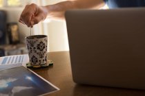 Mann rührt Kaffeebecher zu Hause um — Stockfoto