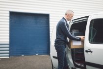Delivery man unloading parcel from delivery van — Stock Photo