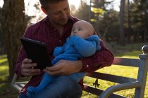 Батько і дитина хлопчик, використовуючи цифровий планшет в парку в сонячний день — стокове фото
