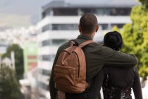 Rear view of couple standing with arm around in city — Stock Photo