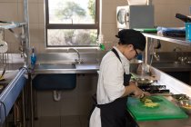 Chef feminino cortando legumes na cozinha no restaurante — Fotografia de Stock
