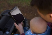 Gros plan du père et du bébé garçon utilisant une tablette numérique dans le parc — Photo de stock