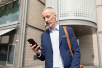 Close-up of businessman using mobile phone in city — Stock Photo