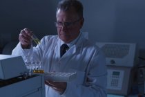 Científico masculino colocando viales médicos en una máquina de laboratorio en el laboratorio - foto de stock