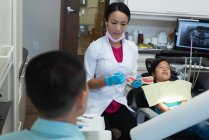 Dentista feminina interagindo com um pai paciente na clínica — Fotografia de Stock
