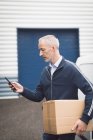 Close-up do homem de entrega usando telefone celular no armazém — Fotografia de Stock