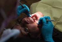 Жіночий стоматолог обстеження хворого з інструментами в стоматологічній клініці — стокове фото