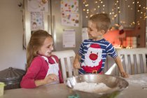 Lächelnde Geschwister spielen in der Küche mit Mehl — Stockfoto