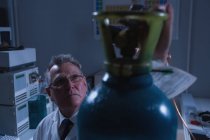 Крупним планом чоловічий вчений регулює манометр циліндра в лабораторії — стокове фото