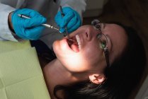 Крупним планом чоловічий стоматолог оглядає пацієнта-леді в клініці — стокове фото