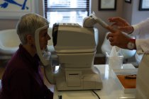 Оптометрист вивчає очі пацієнта з ауторефракторами в клініці — стокове фото