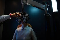 Optometrista examinando os olhos do paciente com phoropter na clínica — Fotografia de Stock