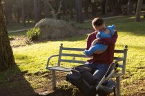 Батько цілувати його хлопчика в парку на сонячний день — стокове фото