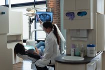 Dentista femenina examinando a una paciente en clínica - foto de stock