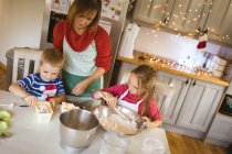 Mother and kids preparing dough for Christmas cookies at home — Stock Photo