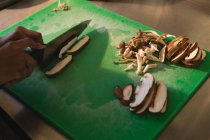 Gros plan du chef coupant des champignons dans la cuisine — Photo de stock