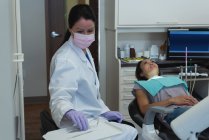 Dentista feminina examinando uma paciente na clínica — Fotografia de Stock