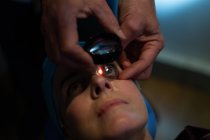 Primer plano del optometrista examinando los ojos del paciente con equipo de prueba ocular en la clínica - foto de stock