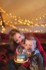 Mother and son holding Christmas tree snow globe at home — Stock Photo