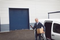 Uomo di consegna utilizzando il telefono cellulare al magazzino — Foto stock