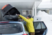 Вид сбоку пожилого человека, держащего сумку на крыше автомобиля — стоковое фото