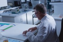 Científico masculino usando nueva tecnología invisible en el escritorio en el laboratorio - foto de stock