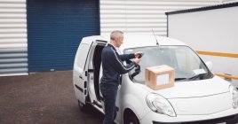 Delivery man using mobile phone at warehouse — Stock Photo