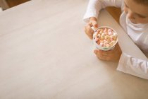 Vista de alto ângulo do menino segurando uma xícara de marshmallows — Fotografia de Stock