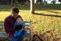 Father and baby boy using digital tablet in the park on a sunny day — Stock Photo